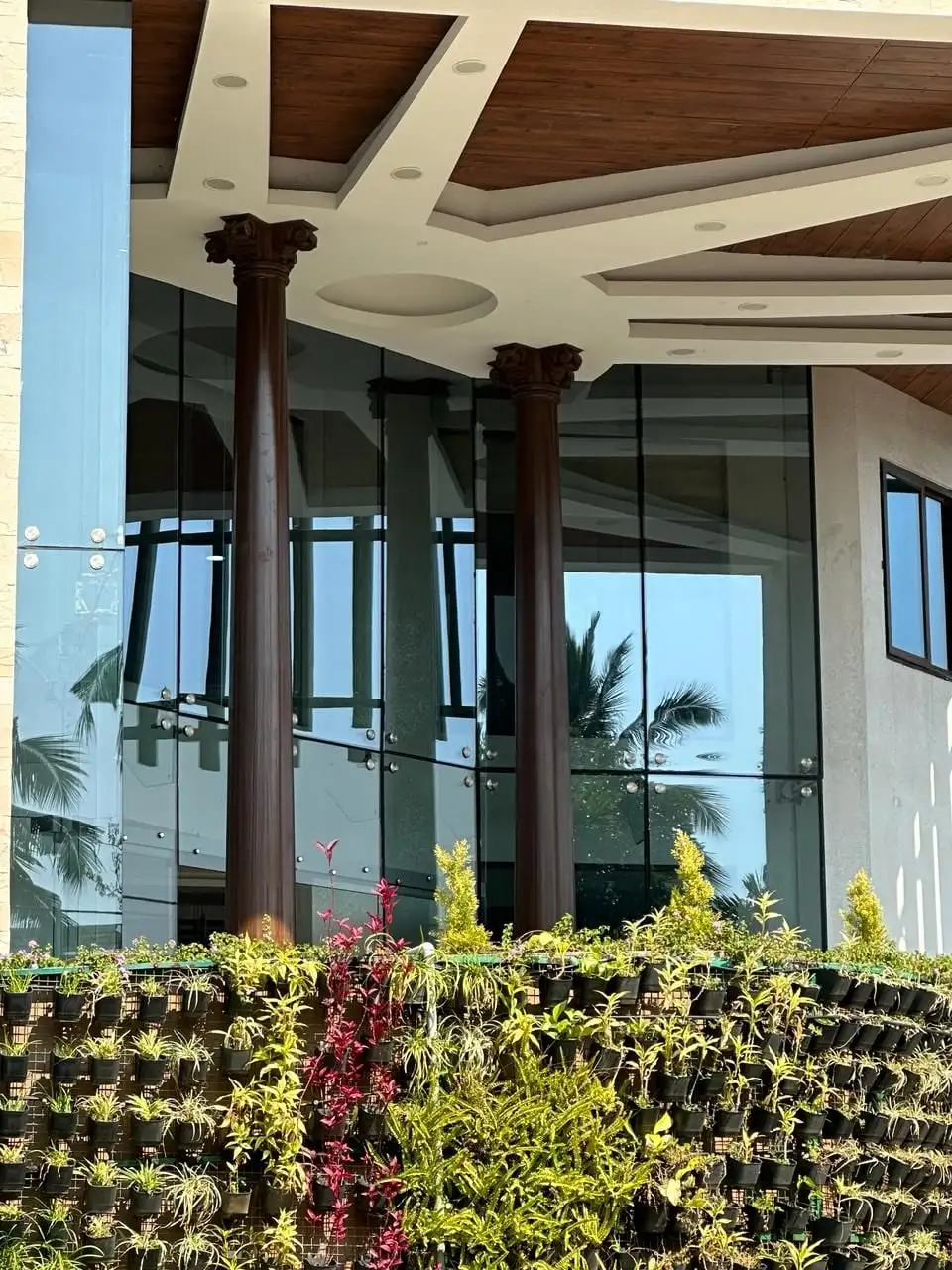 Aayakar Bhavan, Kochi, Kerala: Two columns with carved capitals behind the planted terrace at the entrance