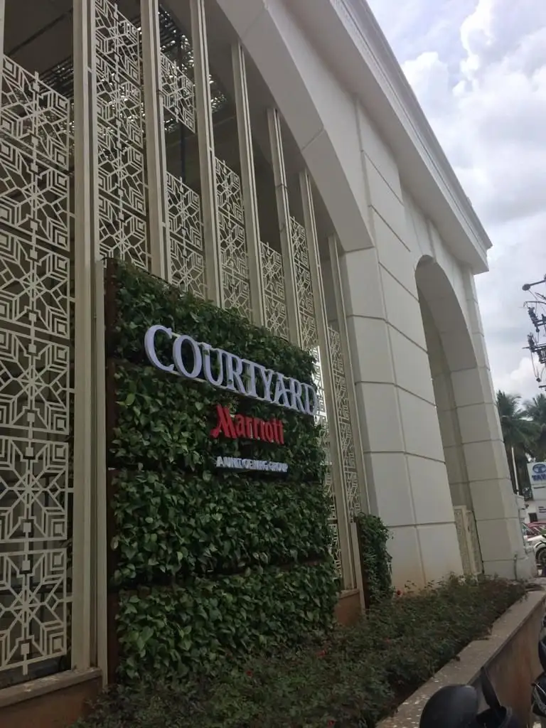 Courtyard by Marriott, Bengaluru: Star-pattern jaali screens beside the green wall and the hotel sign