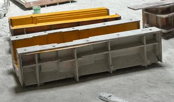 Long fibreglass moulds with a yellow gelcoat face and stiffening ribs, on the workshop floor