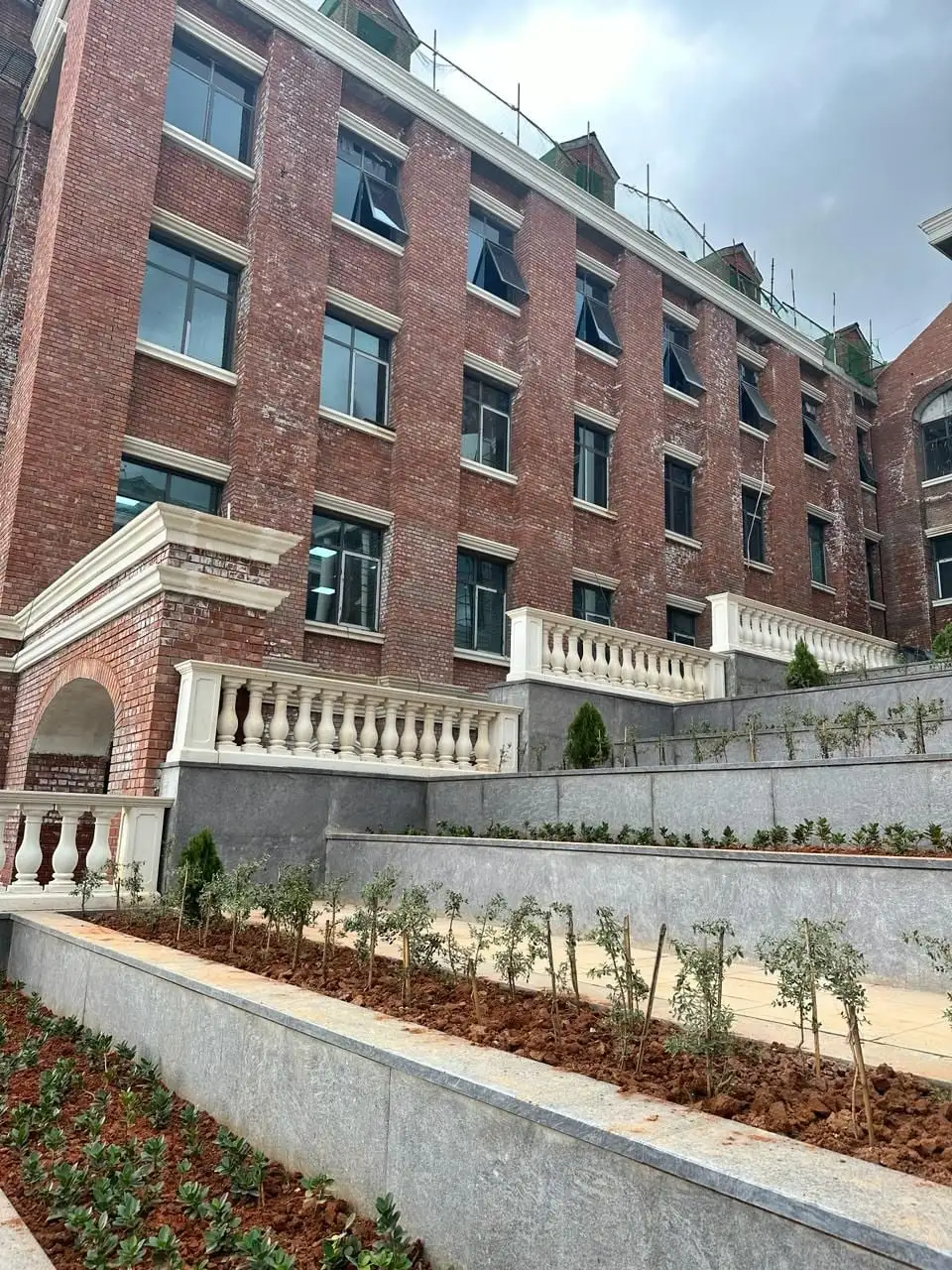 Harrow International School, Devanahalli, Bengaluru: Balustrades, cornices and an arched entrance against the red brick