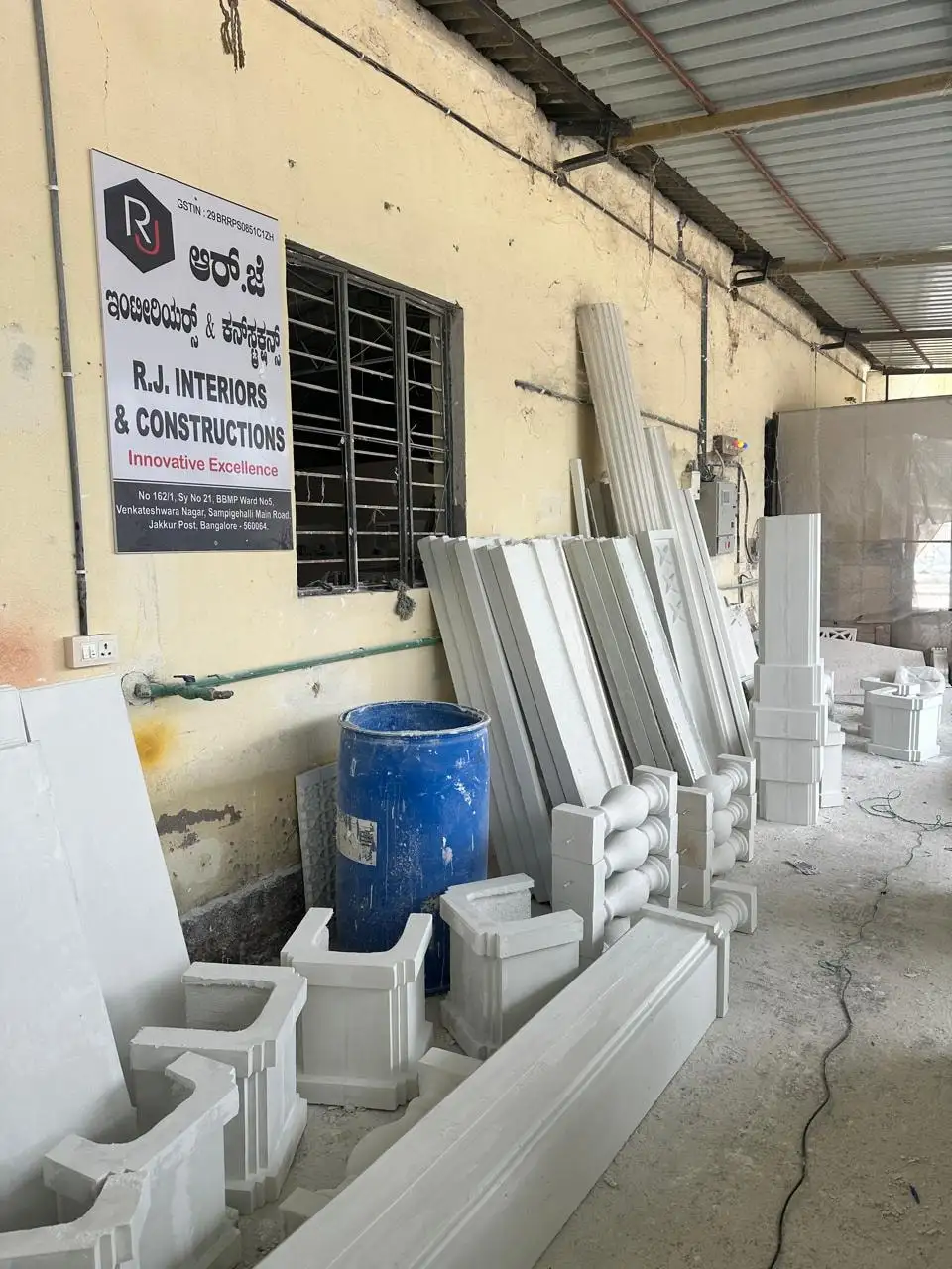 Cast elements stacked against the wall below the RJ Interiors & Constructions signboard