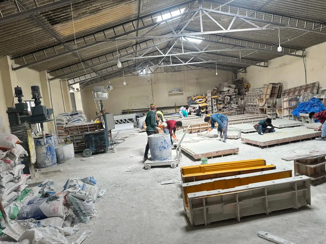 The main workshop hall of RJ Interiors & Constructions in Jakkur, Bangalore, with fibreglass moulds in the foreground and workers finishing panels